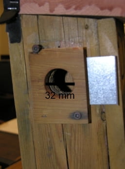 A sliding sheet-metal trapdoor is permanently mounted over the side-entrance hole.